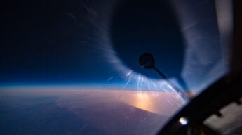 View looking out of a U-2 of the sun being eclipsed by the rear view mirror