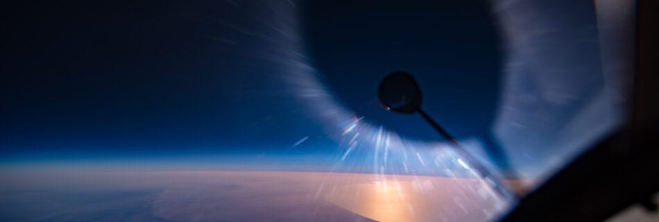 View looking out of a U-2 of the sun being eclipsed by the rear view mirror