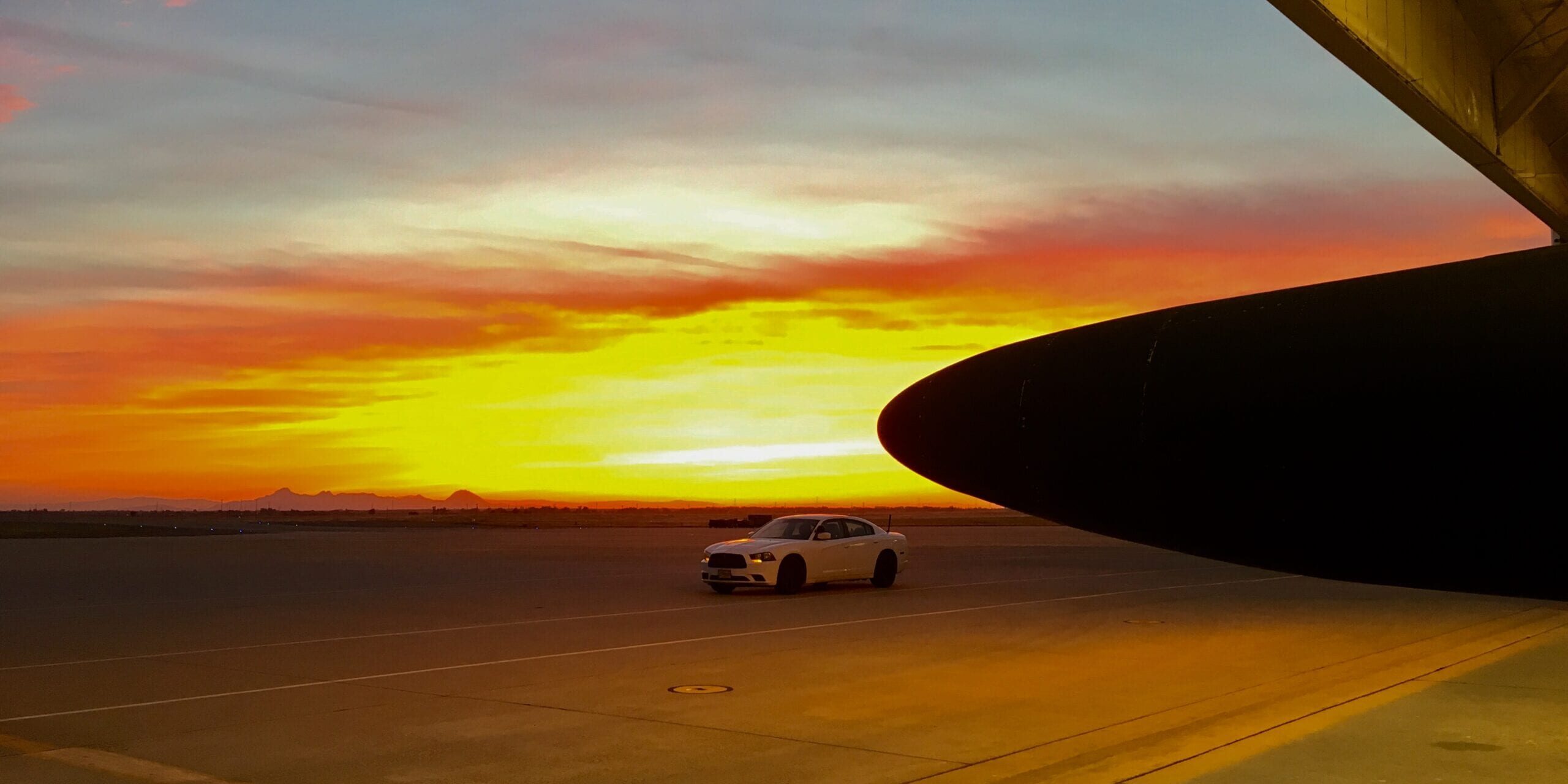 A Dodge Charger sits in the sunset, waiting for the driver